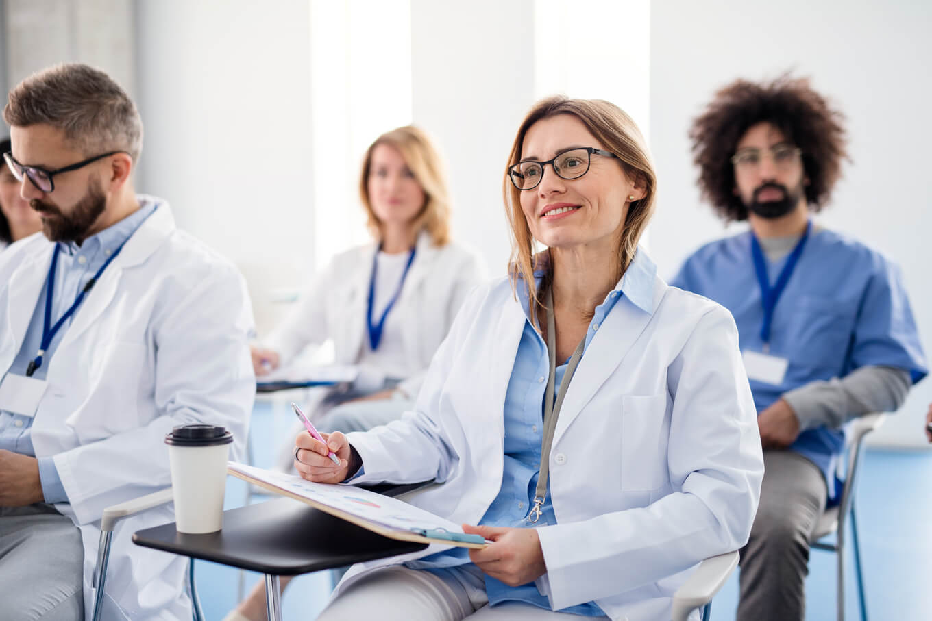 Grupo de médicos inreconhecíveis em conferência, equipe médica sentada e ouvindo.