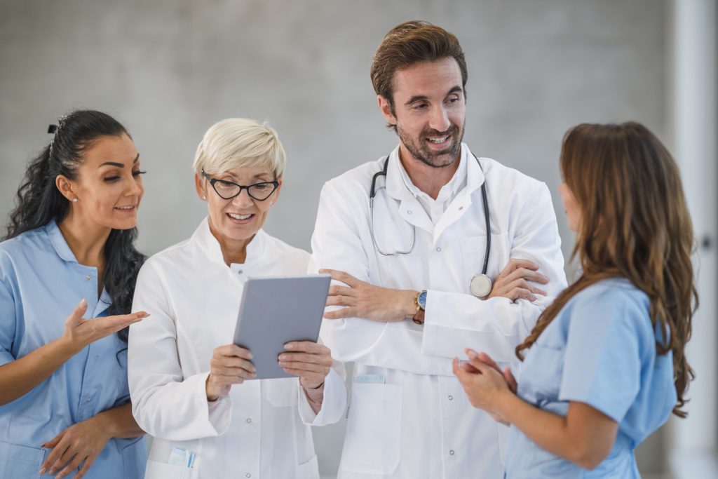 Retrato de uma equipe diversificada de médicos e enfermeiras juntos e usando tablet digital em um hospital.